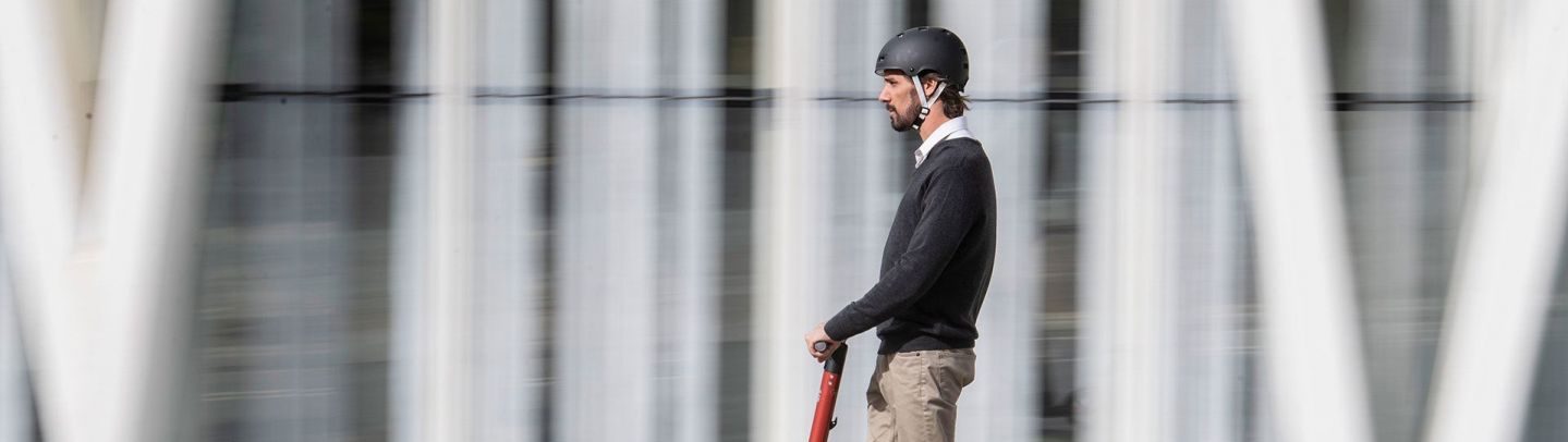 hombre circulando con casco homologado sobre patinete electrico